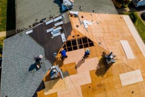 Should I stay home during a roof replacement? Image showing the removal of an old roof and installation of new roofing materials during a roof replacement project.