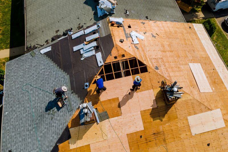 Should I stay home during a roof replacement? Image showing the removal of an old roof and installation of new roofing materials during a roof replacement project.