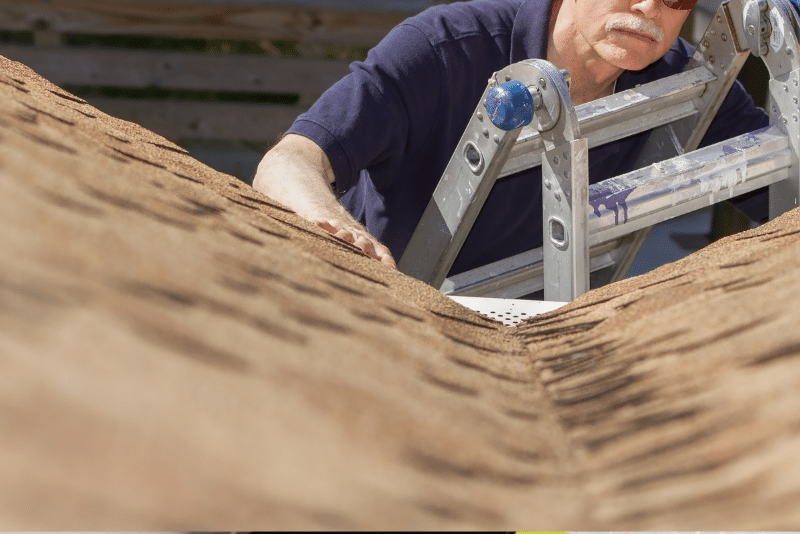 Home inspector examining asphalt shingle roof for signs of structural damage